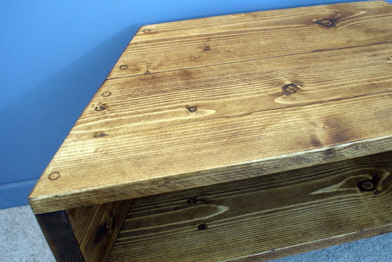 Peut inclure: Banc en bois de forme triangulaire avec une finition naturelle. Le banc est fabriqu&eacute; &agrave; partir de planches de bois, avec des n&oelig;uds et des motifs de grain visibles. Le bois a une teinte brun dor&eacute; chaud, et le banc semble robuste et bien fait.