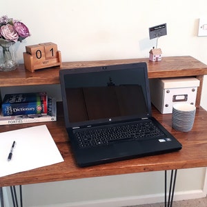 May include: A wooden desk with a black laptop, a white notepad, a pen, a mug, a box, and a wooden calendar that says "01 MAY".