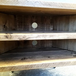 K&ouml;nnte beinhalten: Ein Eck-TV-St&auml;nder aus Holz mit zwei Ablagen und einer abgenutzten Oberfl&auml;che. Der St&auml;nder hat zwei runde L&ouml;cher auf der R&uuml;ckseite f&uuml;r die Kabelverwaltung.