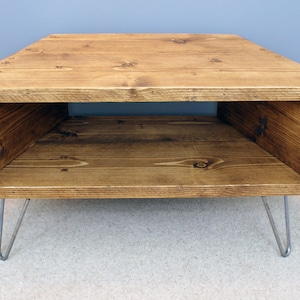 Peut inclure: Table basse en bois rustique avec un plateau rectangulaire et une &eacute;tag&egrave;re ouverte. La table est teint&eacute;e d'une couleur marron chaud et poss&egrave;de des pieds en &eacute;pingle &agrave; cheveux en m&eacute;tal. Mesure environ 76 cm de long, 46 cm de large et 41 cm de haut.