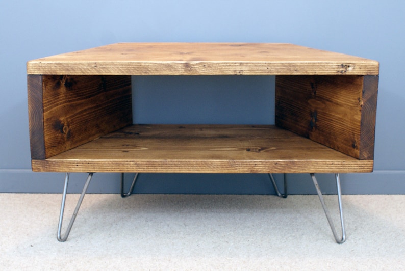 Peut inclure: Table basse rectangulaire en bois avec une finition naturelle. La table a un centre creux et est soutenue par quatre pieds en &eacute;pingle &agrave; cheveux argent&eacute;s. Le grain du bois est visible. Dimensions: environ 90 cm x 60 cm.