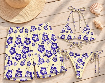 May include: A set of swimwear consisting of a pair of shorts and a two-piece bikini, all featuring a light yellow base with a dark blue hibiscus floral pattern. The bikini top has triangle cups and ties, while the bikini bottom has side ties.