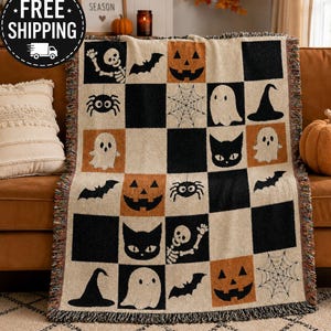 May include: A woven throw blanket featuring a checkered pattern of black, cream, and orange squares. The design includes Halloween-themed motifs such as jack-o'-lanterns, ghosts, black cats, spiders, spiderwebs, bats, skeletons, and witch hats.