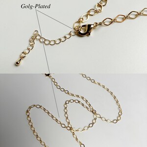May include: Gold-plated chain necklace with a lobster clasp closure. The chain is made of small, oval-shaped links.
