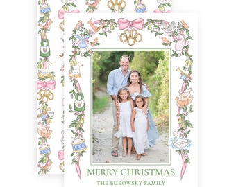 Pode incluir: Um cartão de Natal retangular com uma foto central de uma família de quatro pessoas rodeada por uma borda decorativa de motivos ilustrados dos doze dias de Natal, laços cor-de-rosa e anéis dourados. O texto diz MERRY CHRISTMAS, THE BUKOWSKY FAMILY, 2025.
