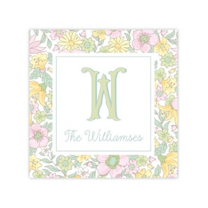 Puede incluir: Una tarjeta blanca con un borde floral y un monograma verde "W" con el texto "The Williamses" en una fuente cursiva.