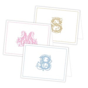 Puede incluir: Tres tarjetas plegadas con monogramas iniciales decorativos. La primera tarjeta tiene un monograma "M" rosa, la segunda tarjeta tiene un monograma "S" dorado y la tercera tarjeta tiene un monograma "B" azul.