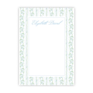 May include: A rectangular notepad with a white background, featuring a light blue and green floral border and vertical stripes. The name "Elizabeth Diard" is written in cursive in the center.