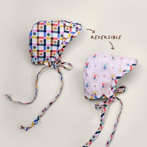 Reversible baby bonnet with brim, showing gingham side and floral side laid flat, handmade from organic cotton