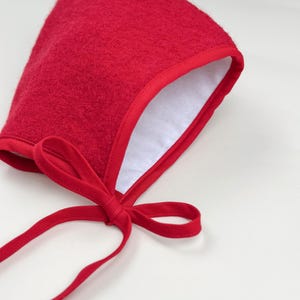 Close-up of Cranberry boiled wool pixie bonnet showing soft white flannel lining and matching cotton trim.