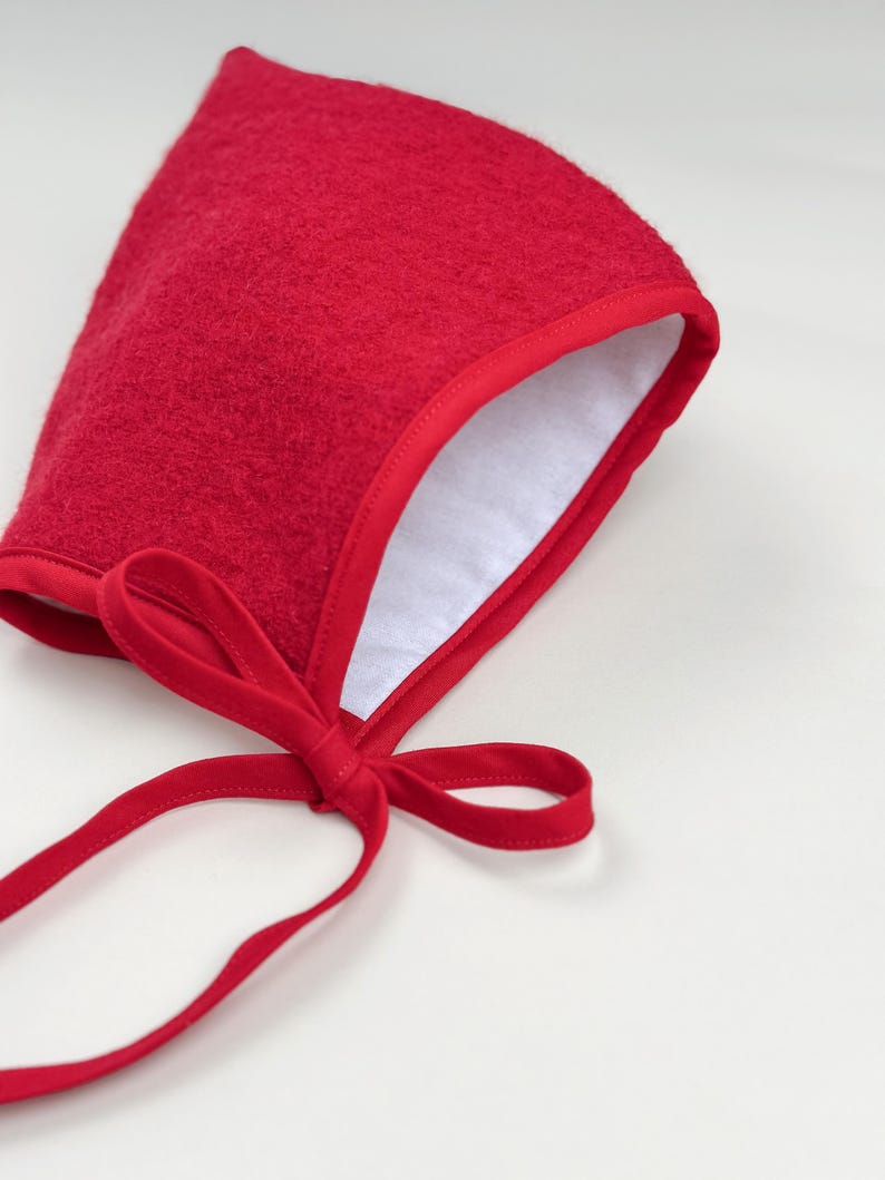 Close-up of Cranberry boiled wool pixie bonnet showing soft white flannel lining and matching cotton trim.