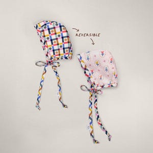 Reversible brimless baby bonnet, showing gingham side and floral side laid flat, handmade from organic cotton