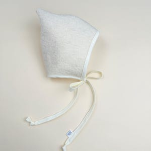 Snowdrop boiled wool pixie bonnet with light cream trim and ties, minimalist handmade baby hat.