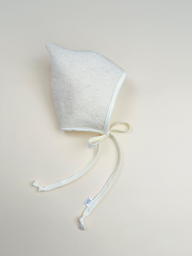 Snowdrop boiled wool pixie bonnet with light cream trim and ties, minimalist handmade baby hat.
