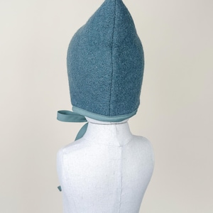 Back view of Juniper boiled wool pixie bonnet on mannequin, showing seam and pointed top.