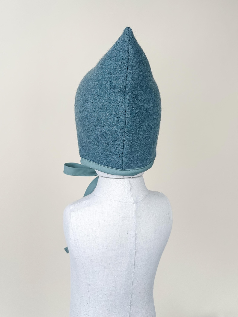 Back view of Juniper boiled wool pixie bonnet on mannequin, showing seam and pointed top.