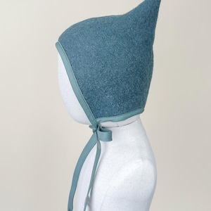 Side view of Juniper boiled wool pixie bonnet on mannequin, showing shape and fit over ears.