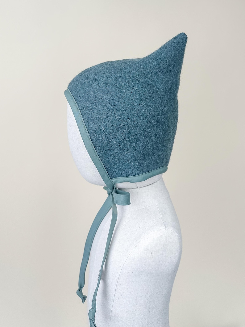 Side view of Juniper boiled wool pixie bonnet on mannequin, showing shape and fit over ears.
