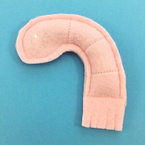 May include: A pink felt hand puppet shaped like a shrimp. The puppet has a stitched seam down the centre of the body and a fringe at the bottom.