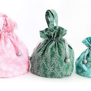 以下が含まれることがあります： 3つの異なるサイズの巾着袋。一番大きい袋は白の葉柄のピンク。中くらいの袋は白の葉柄の緑。一番小さい袋は白の葉柄のターコイズブルーです。