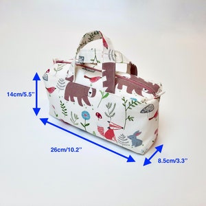 May include: A white fabric tote bag with a pink handle and a woodland animal print. The bag measures 10.2 inches wide, 5.5 inches tall, and 3.3 inches deep.