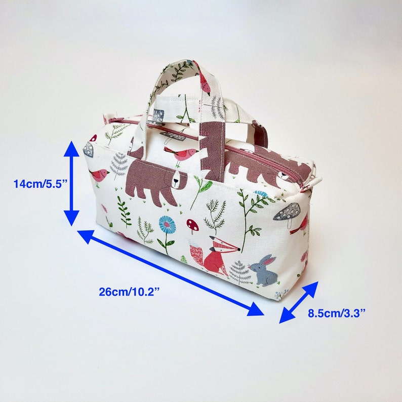 May include: A white fabric tote bag with a pink handle and a woodland animal print. The bag measures 10.2 inches wide, 5.5 inches tall, and 3.3 inches deep.