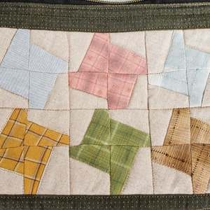 May include: A green fabric zippered pouch with a patchwork design. The front of the pouch is made of beige fabric with six different coloured squares, each with a star-shaped design. The squares are in shades of blue, pink, yellow, green, and brown.