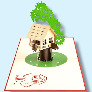 Op de afbeelding: Een pop-up wenskaart met een boomhutontwerp. De boomhut is gemaakt van lichtbruin hout, met een groene bladerkroon. De open kaart onthult een groene cirkel met kleine witte vogels en een rode rand, waardoor een 3D-effect ontstaat.