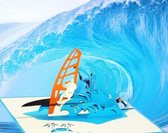 May include: A blue and white 3D pop-up card featuring a person windsurfing on a wave with palm trees in the background.
