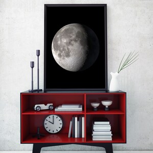May include: A red and black bookshelf with three shelves. The top shelf has a toy car, two small bowls, and a framed black and white photo of the moon. The middle shelf has a clock and books. The bottom shelf has more books.