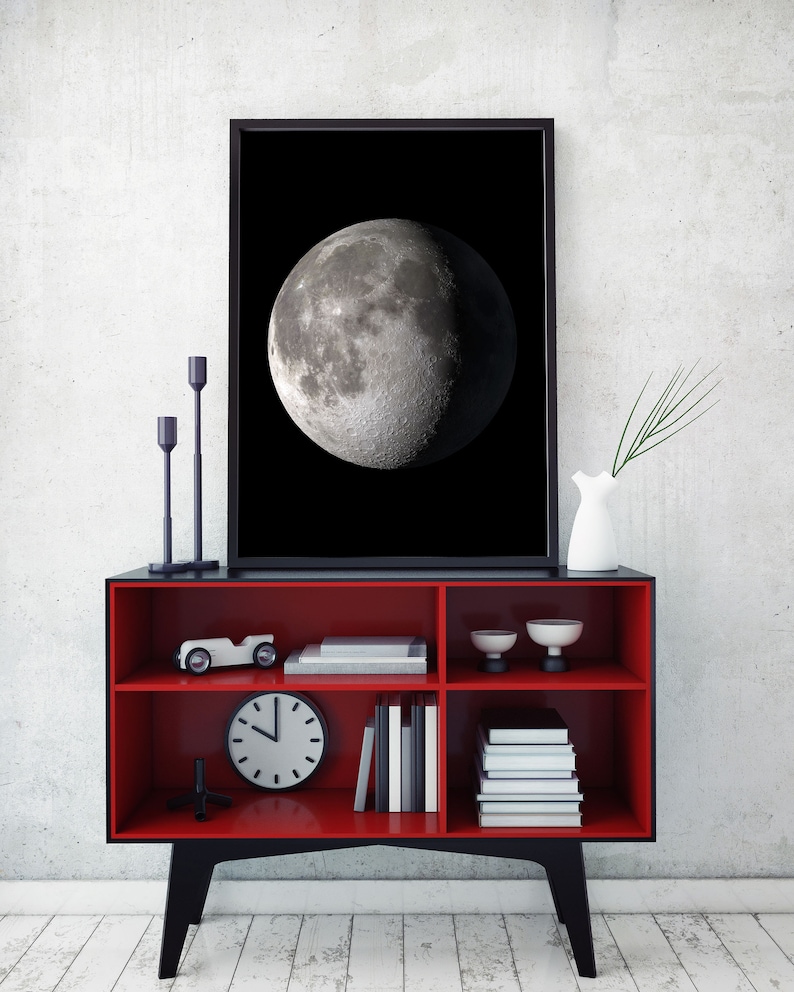 May include: A red and black bookshelf with three shelves. The top shelf has a toy car, two small bowls, and a framed black and white photo of the moon. The middle shelf has a clock and books. The bottom shelf has more books.