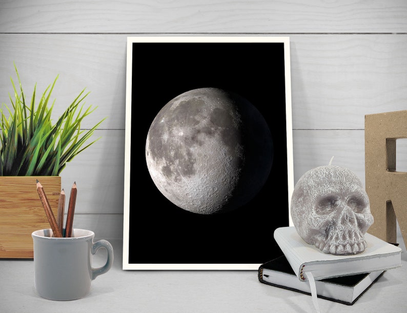 May include: A black and white photograph of a crescent moon against a dark background. The moon is in the center of the image and is the main focus.