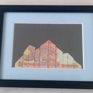 Puede incluir: Una obra de arte enmarcada que presenta un collage de billetes de rupias indias dispuestos para formar un edificio. Los billetes son en tonos naranja, amarillo y verde, y el texto "TEN RUPEES" es visible en la esquina inferior derecha.