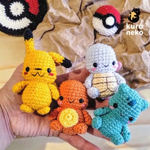 Op de afbeelding: Vijf gehaakte knuffels in verschillende kleuren en ontwerpen. De knuffels zijn een gele Pikachu, een blauwe schildpad, een oranje Squirtle, een groene Bulbasaur en een rode Pokébal. De knuffels liggen op een hand.