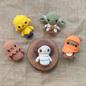 Può includere: Un set di sei personaggi di Star Wars all'uncinetto, tra cui Yoda, la principessa Leia, Chewbacca, R2-D2, C-3PO e uno Stormtrooper. I personaggi sono tutti realizzati con filati di diversi colori e hanno caratteristiche dettagliate.