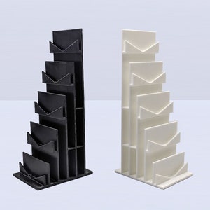 May include: Two magazine holders, one black and one white, with a stepped design. Each holder has five slots for magazines or papers.