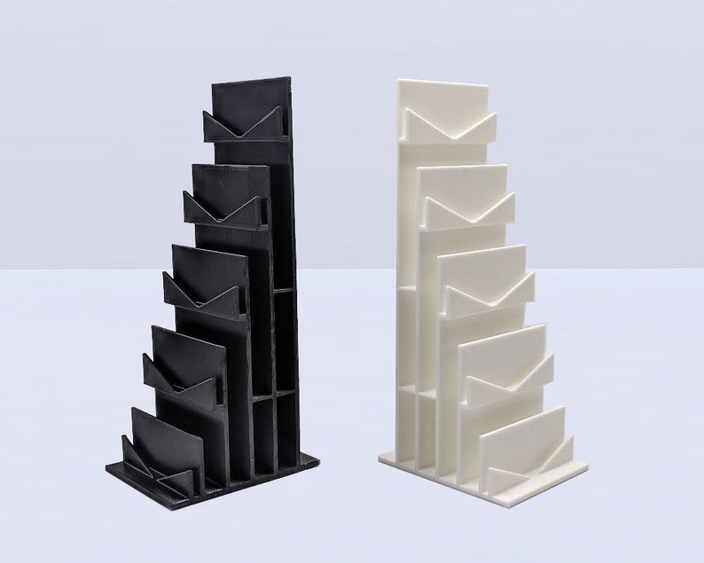 May include: Two magazine holders, one black and one white, with a stepped design. Each holder has five slots for magazines or papers.