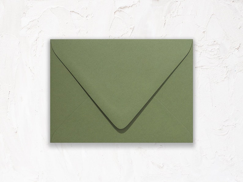 May include: A single, olive green envelope, viewed from above, against a white textured background. The envelope is rectangular with a pointed flap closure. The paper has a matte finish.