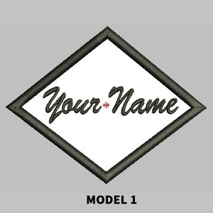Pode incluir: Um remendo preto em forma de diamante com fundo branco e o texto "Your Name" em uma fonte cursiva preta.