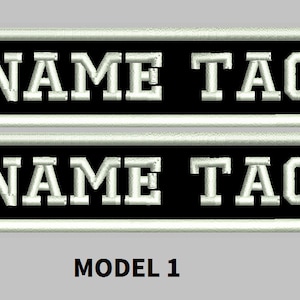 May include: Two black and white embroidered patches with the text "NAME TAG" in white lettering. The patches are rectangular and have a white border. The text "MODEL 1" is printed below the patches.