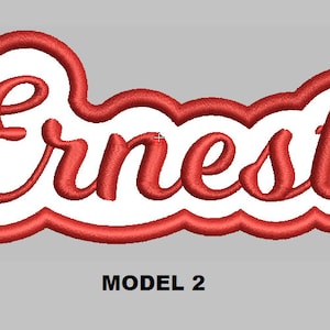 Könnte beinhalten: Roter gestickter Namens-Patch mit dem Namen "Ernest" in weißer Umrandung. Der Patch hat eine abgerundete, blasenartige Form.