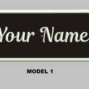 Könnte beinhalten: Weißer Text auf schwarzem Hintergrund mit weißem Rand lautet "Your Name". Der Text ist in einer kursiven Schriftart. Der Patch ist mit "MODEL 1" gekennzeichnet.