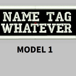 Puede incluir: Parche bordado con las palabras "NAME TAG WHATEVER" en letras blancas sobre fondo negro, enmarcado por un borde blanco. El texto "MODEL 1" está debajo.