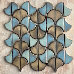 May include: A geometric pattern of blue and brown ceramic tiles arranged in a repeating pattern. The tiles are shaped like half-circles and are arranged in a staggered pattern.