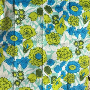 May include: A blue and green floral fabric with a repeating pattern of flowers, leaves, and buds. The fabric has a light blue background with green and blue flowers.