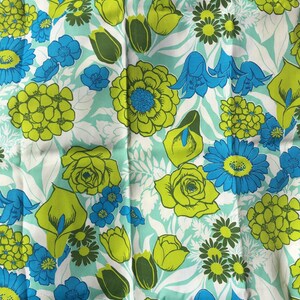 May include: A fabric with a repeating pattern of green, yellow, and blue flowers on a light blue background.