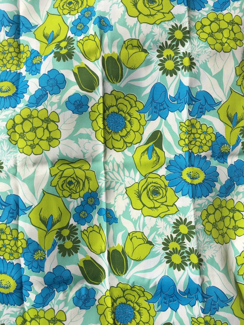 May include: A fabric with a repeating pattern of green, yellow, and blue flowers on a light blue background.