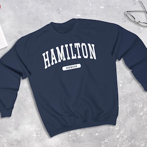 Peut inclure: Un sweat-shirt bleu marine avec le texte "HAMILTON BERMUDA" en blanc.