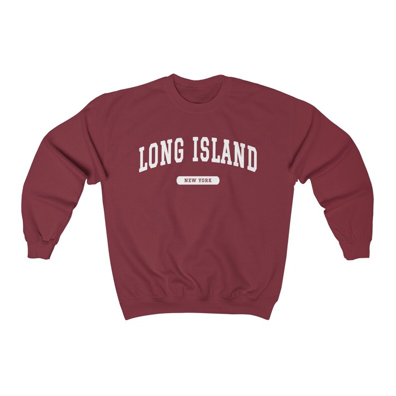 K&ouml;nnte beinhalten: Ein weinroter Pullover mit dem Text "LONG ISLAND" in Wei&szlig;, darunter "NEW YORK" in einem kleineren wei&szlig;en Rechteck.