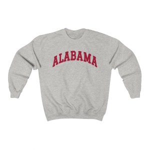 K&ouml;nnte beinhalten: Ein grauer Pullover mit dem Wort "ALABAMA" in Rot auf der Vorderseite.
